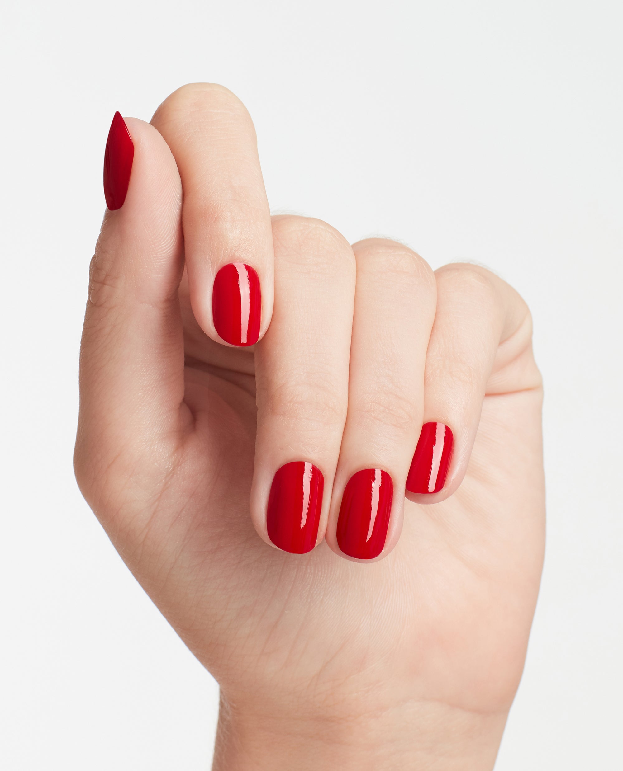 Hand showing neatly manicured nails painted in OPI Big Apple Red nail lacquer, the glossy classic red shade highlighted against a clean white background, ideal for showcasing an OPI nail polish gift set color result.